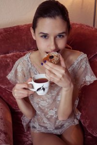 Девушка в прозрачной блузке пьет чай